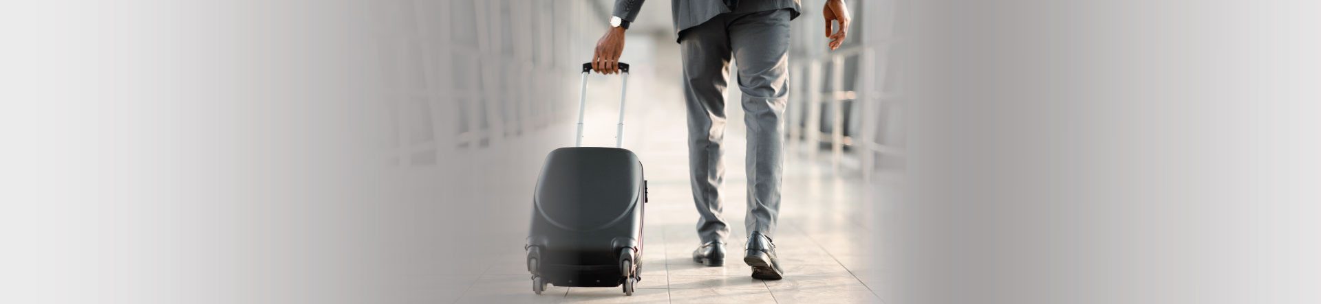 Businessman in a suit wheeling along a suitcase