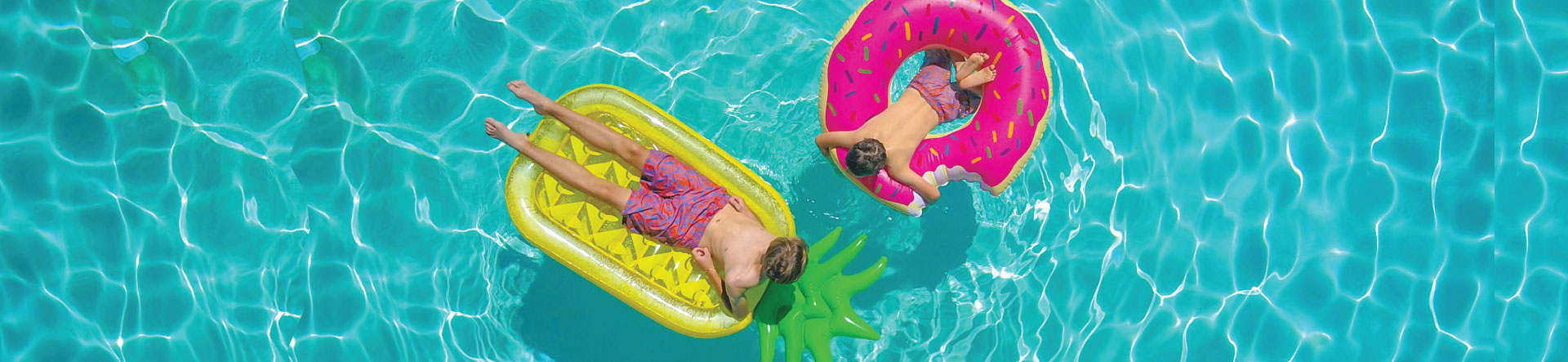 Travel Tech - boys on holiday floating on inflatables in a swimming pool