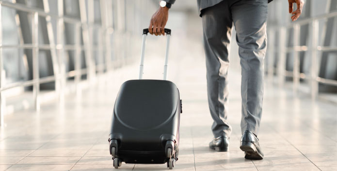 Businessman in a suit wheeling along a suitcase