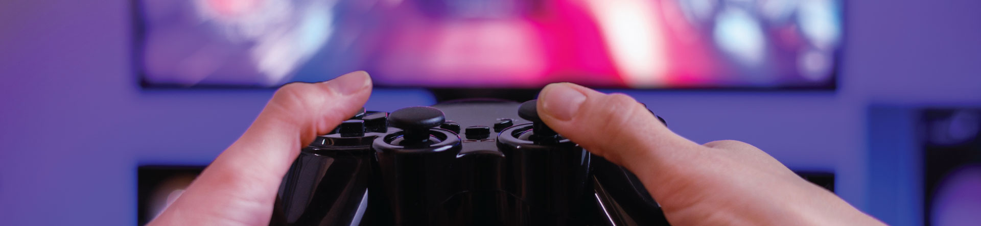 Hands holding a gaming PC controller in front of a screen
