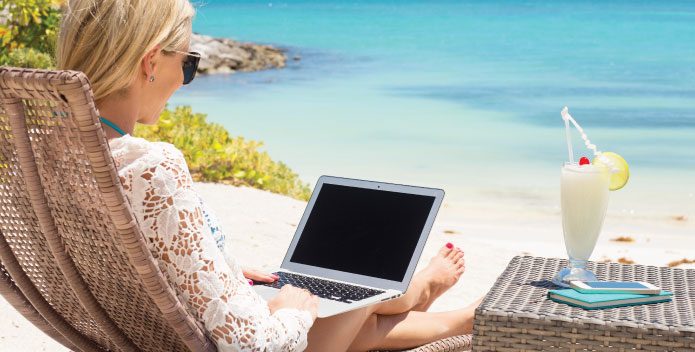 Holiday Working - sitting on the beach with laptop and cocktail