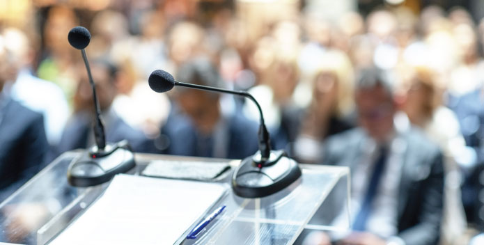 A podium with microphones looking out to the conference floor where delegates are sitting