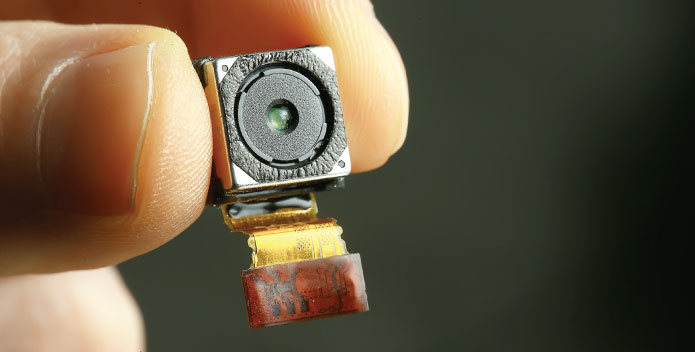 Travel Tech Guide 2023 - a miniture spy camera being held between a thumb and forefinger